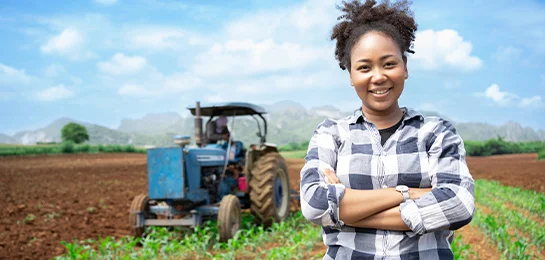 A lady posing in front of a tractor. 