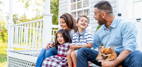 A family sitting on the porch of their new house.